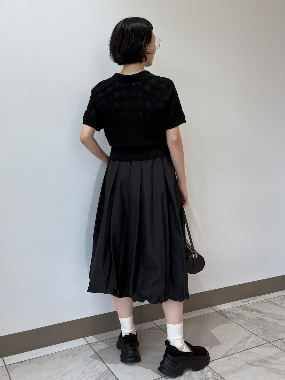 ブラック系のポロシャツ、ブラック系のスカート、ブラウン系のショルダーバッグを着用したレディースの夏コーディネートの5枚目の写真