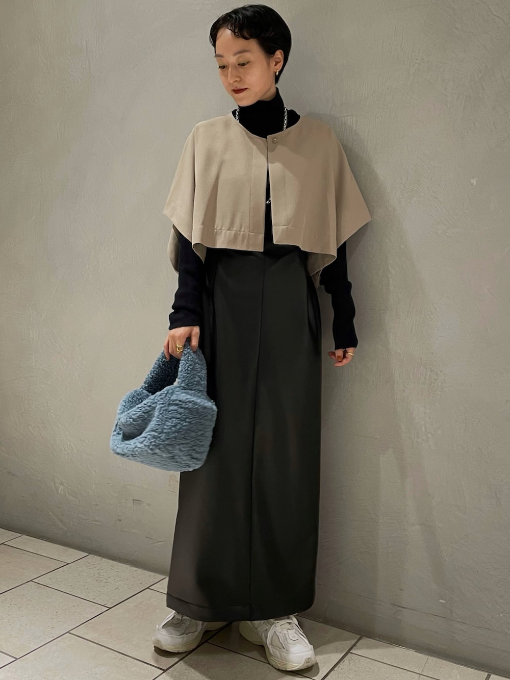 ブラック系のニット/セーター、グリーン系のトレンチコート、ブルー系のハンドバッグを着用したレディースの秋コーディネートの2枚目の写真