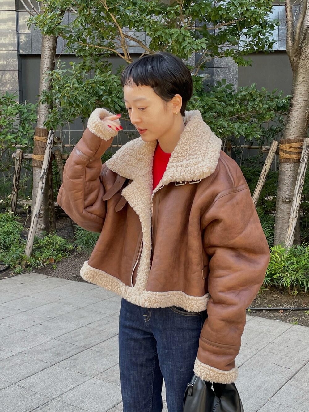 レッド系のニット/セーター、ブラック系のショルダーバッグ、ブラック系のスニーカーを着用したレディースの冬コーディネートの3枚目の写真