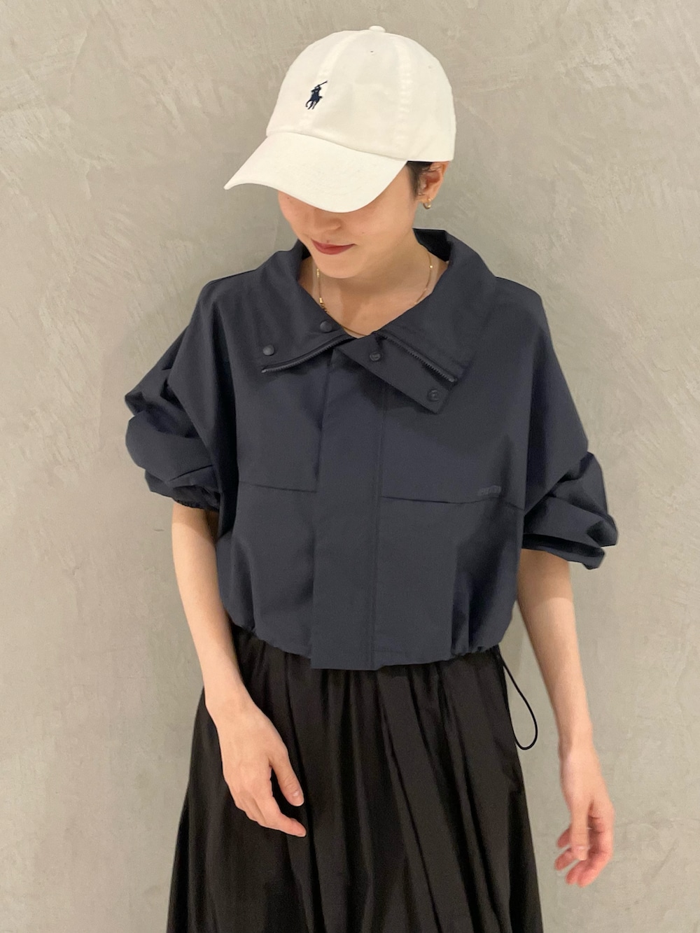 ブルー系のナイロンジャケット、ブラック系のスカート、ベージュ系のスニーカーを着用したレディースの春コーディネートの4枚目の写真