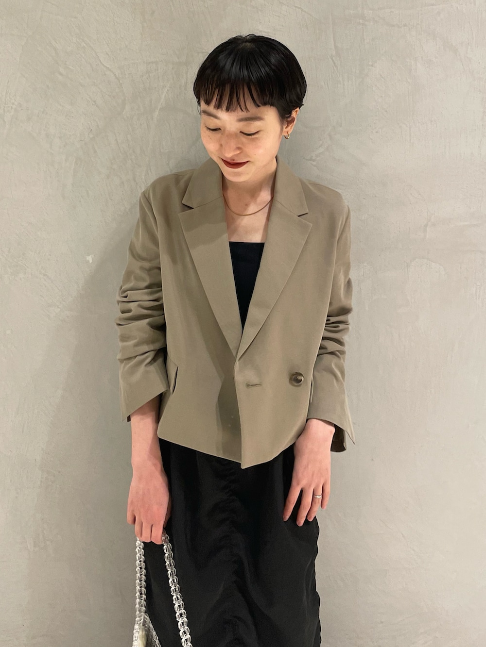 グリーン系のテーラードジャケット、ブラック系のキャミソール、ブラック系のスカートを着用したレディースの春コーディネートの4枚目の写真
