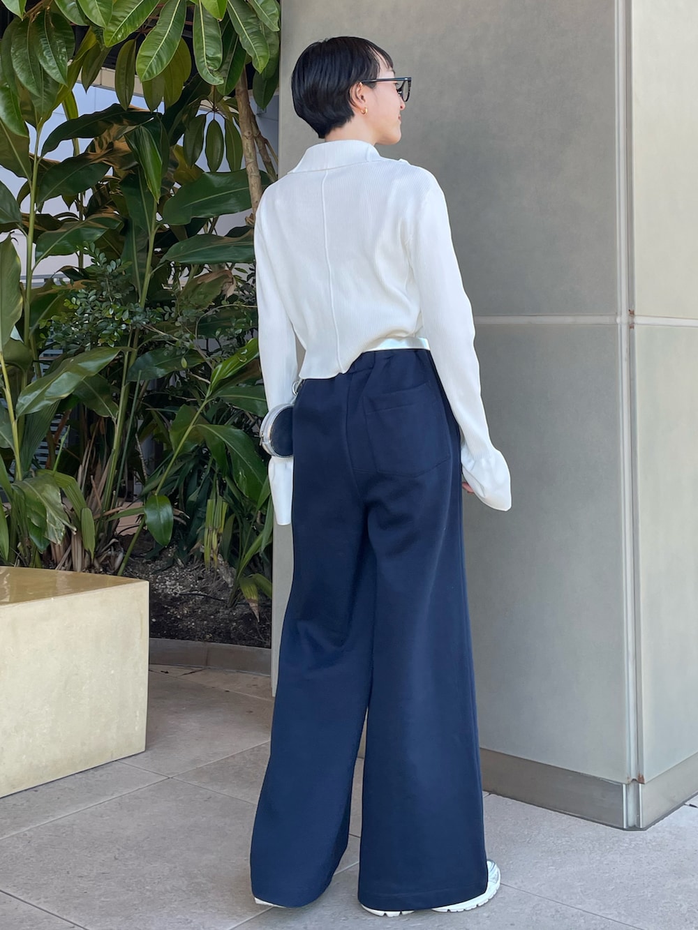 ホワイト系のニット/セーター、シルバー系のボディバッグ/ウエストポーチ、ブルー系のスウェットパンツを着用したレディースの冬コーディネートの3枚目の写真