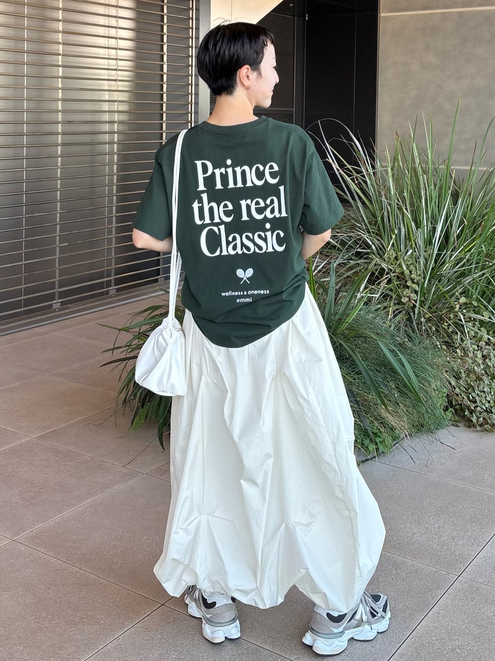 グリーン系のTシャツ/カットソー、ホワイト系のスカート、ブラウン系のスニーカーを着用したレディースの夏コーディネートの2枚目の写真