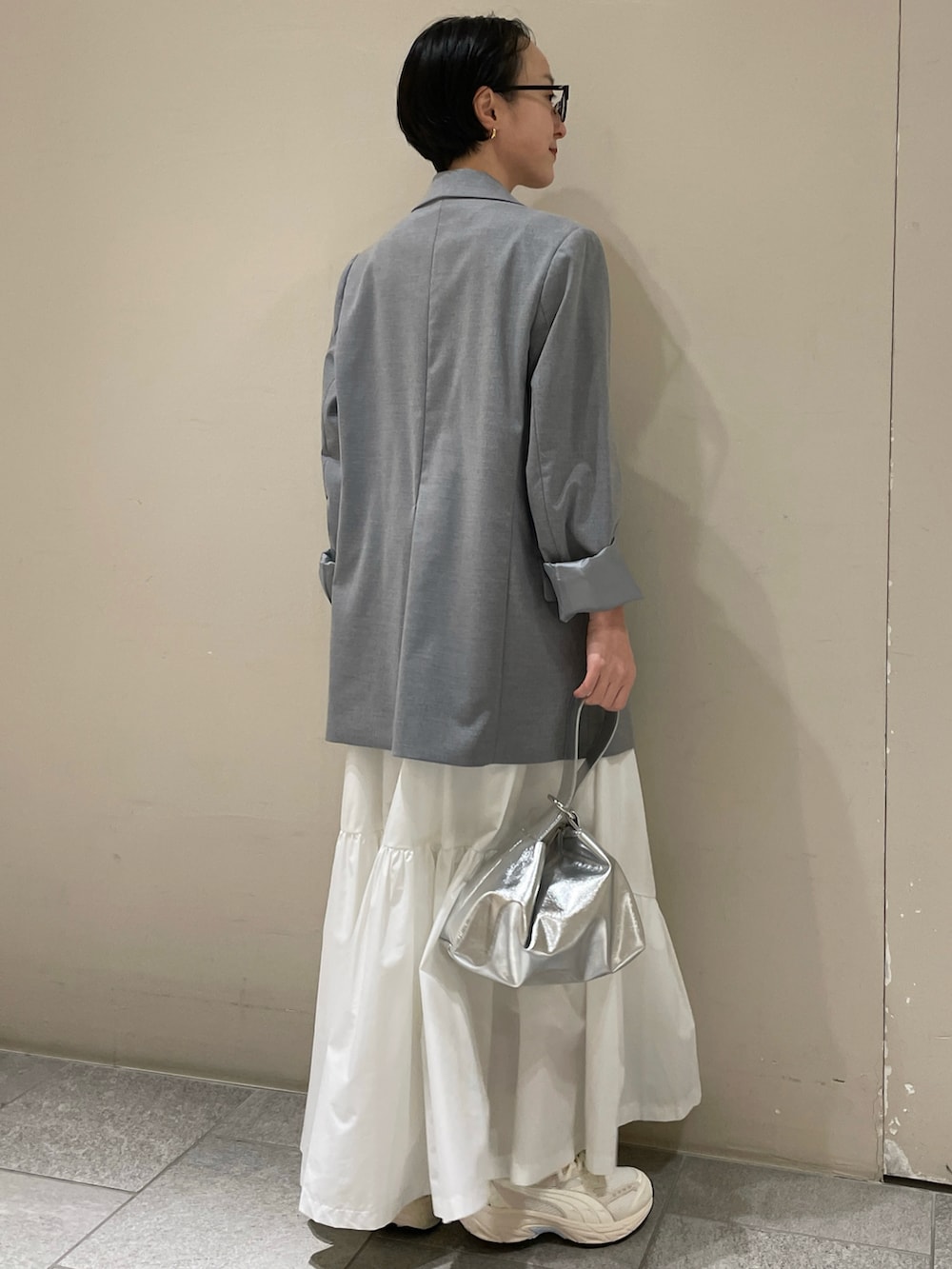 グレー系のテーラードジャケット、ホワイト系のTシャツ/カットソー、ホワイト系のスカートを着用したレディースの冬コーディネートの3枚目の写真