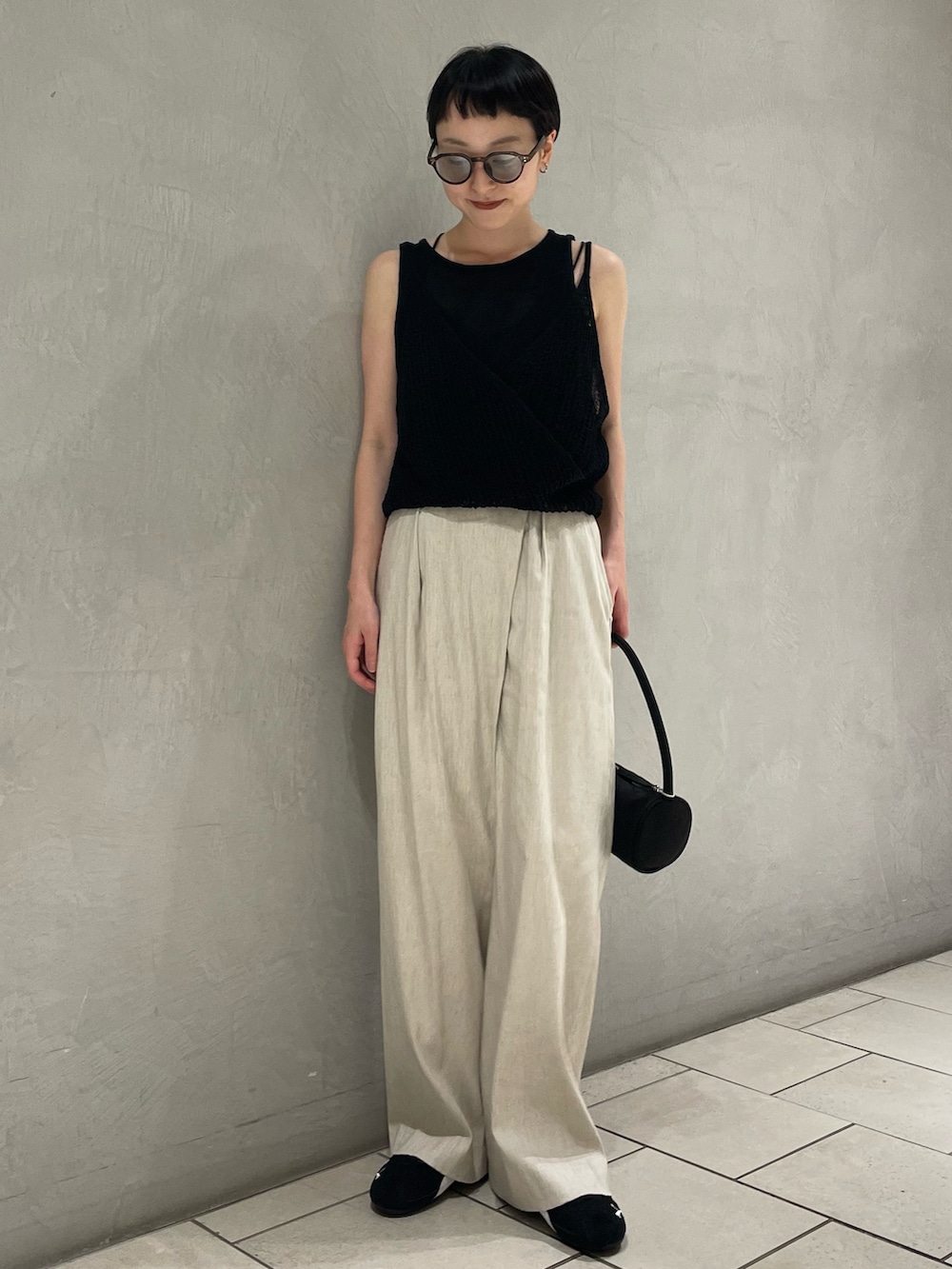 ブラック系のニット/セーター、ベージュ系のその他パンツ、ブラック系のハンドバッグを着用したレディースの春コーディネートの2枚目の写真