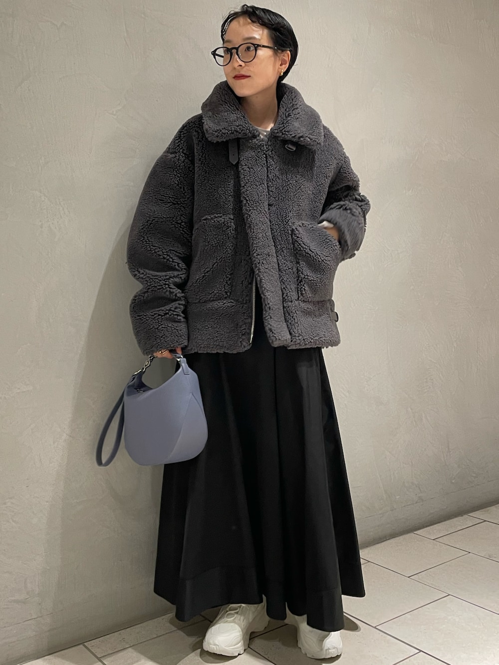 グレー系のブルゾン、ブラック系のスカート、ブルー系のショルダーバッグを着用したレディースの冬コーディネートの2枚目の写真