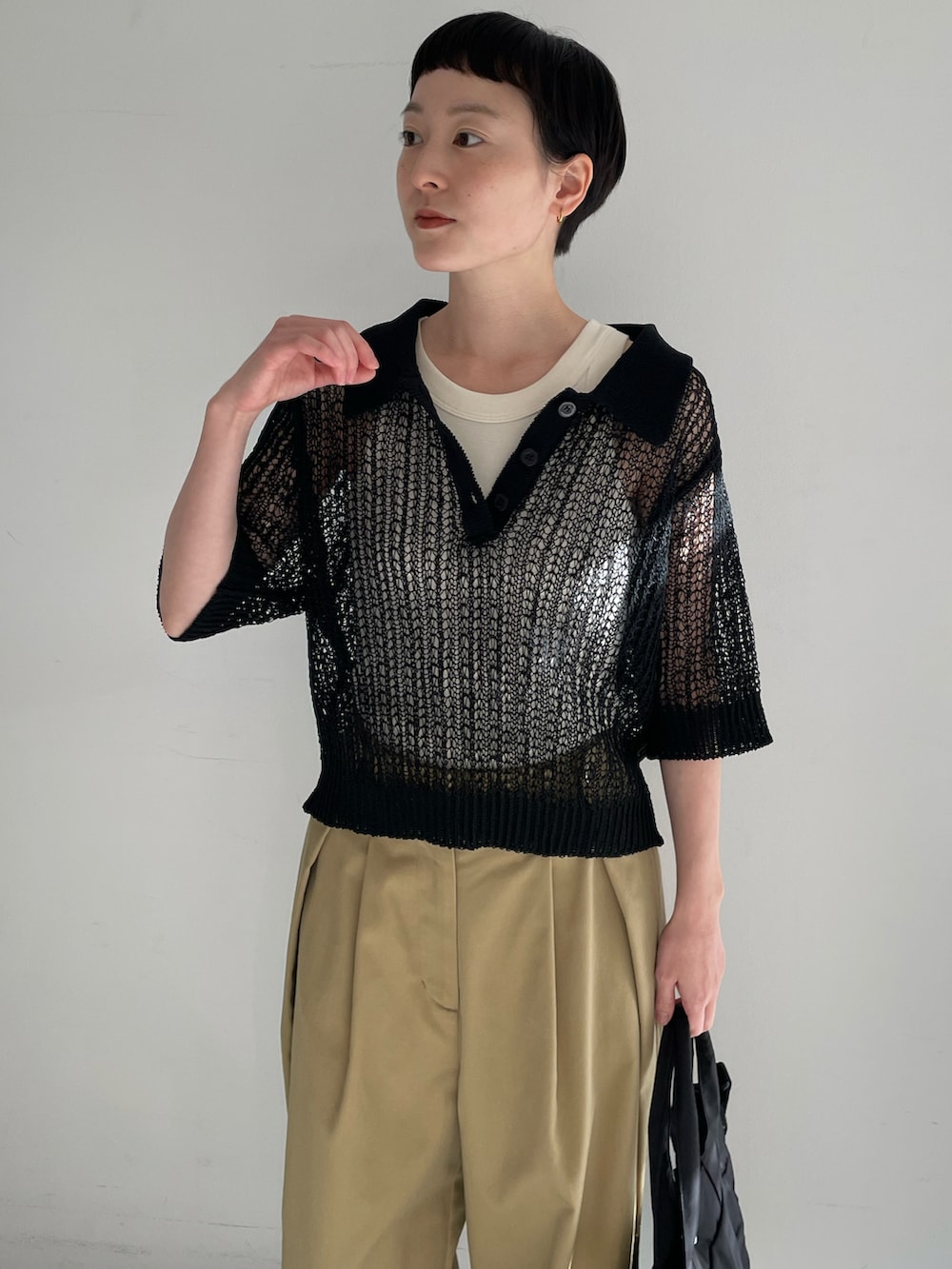 ホワイト系のタンクトップ、ブラック系のニット/セーター、ベージュ系のチノパンツを着用したレディースの春コーディネートの2枚目の写真