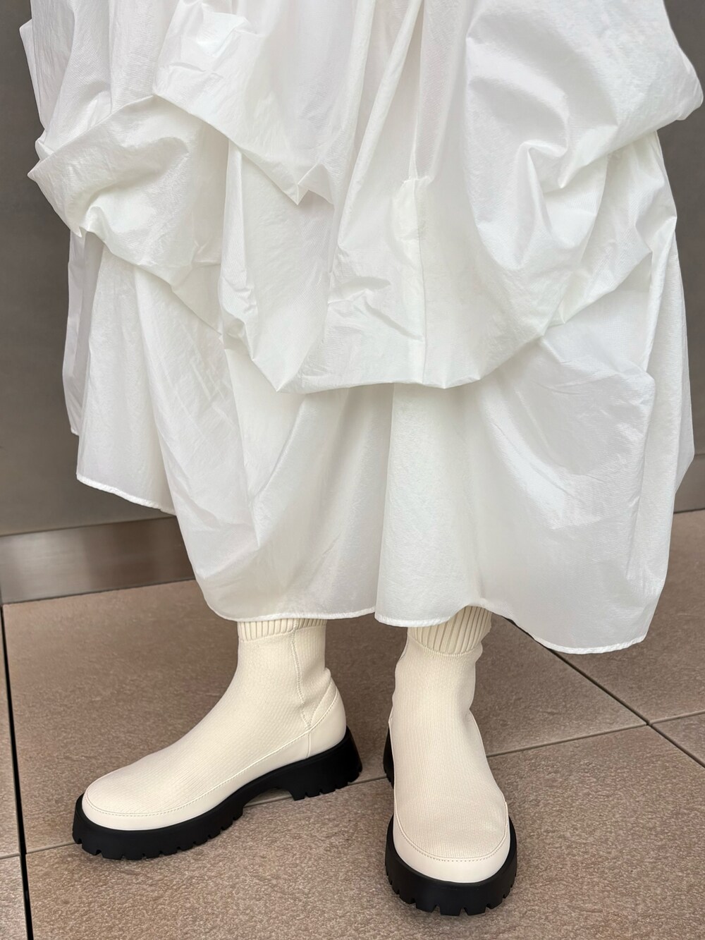 ブルー系のニット/セーター、ホワイト系のスカート、グリーン系のボストンバッグを着用したレディースの秋コーディネートの5枚目の写真