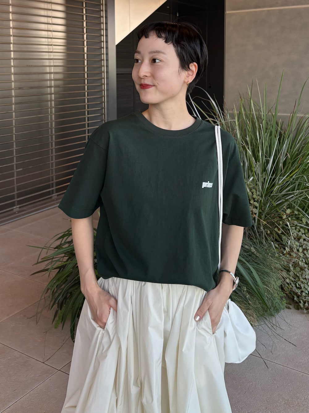 グリーン系のTシャツ/カットソー、ホワイト系のスカート、ブラウン系のスニーカーを着用したレディースの夏コーディネートの4枚目の写真