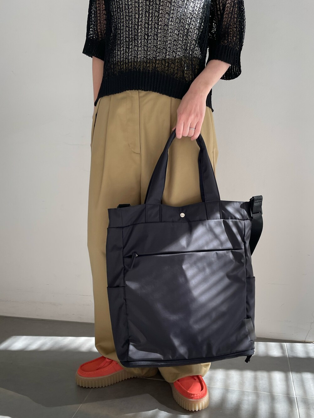 ホワイト系のタンクトップ、ブラック系のニット/セーター、ベージュ系のチノパンツを着用したレディースの春コーディネートの5枚目の写真