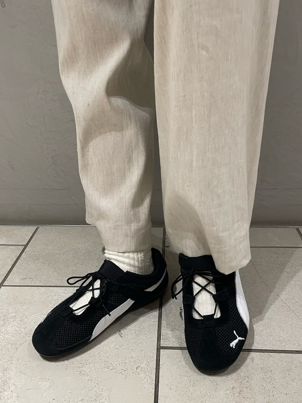 ブラック系のニット/セーター、ベージュ系のその他パンツ、ブラック系のハンドバッグを着用したレディースの春コーディネートの5枚目の写真