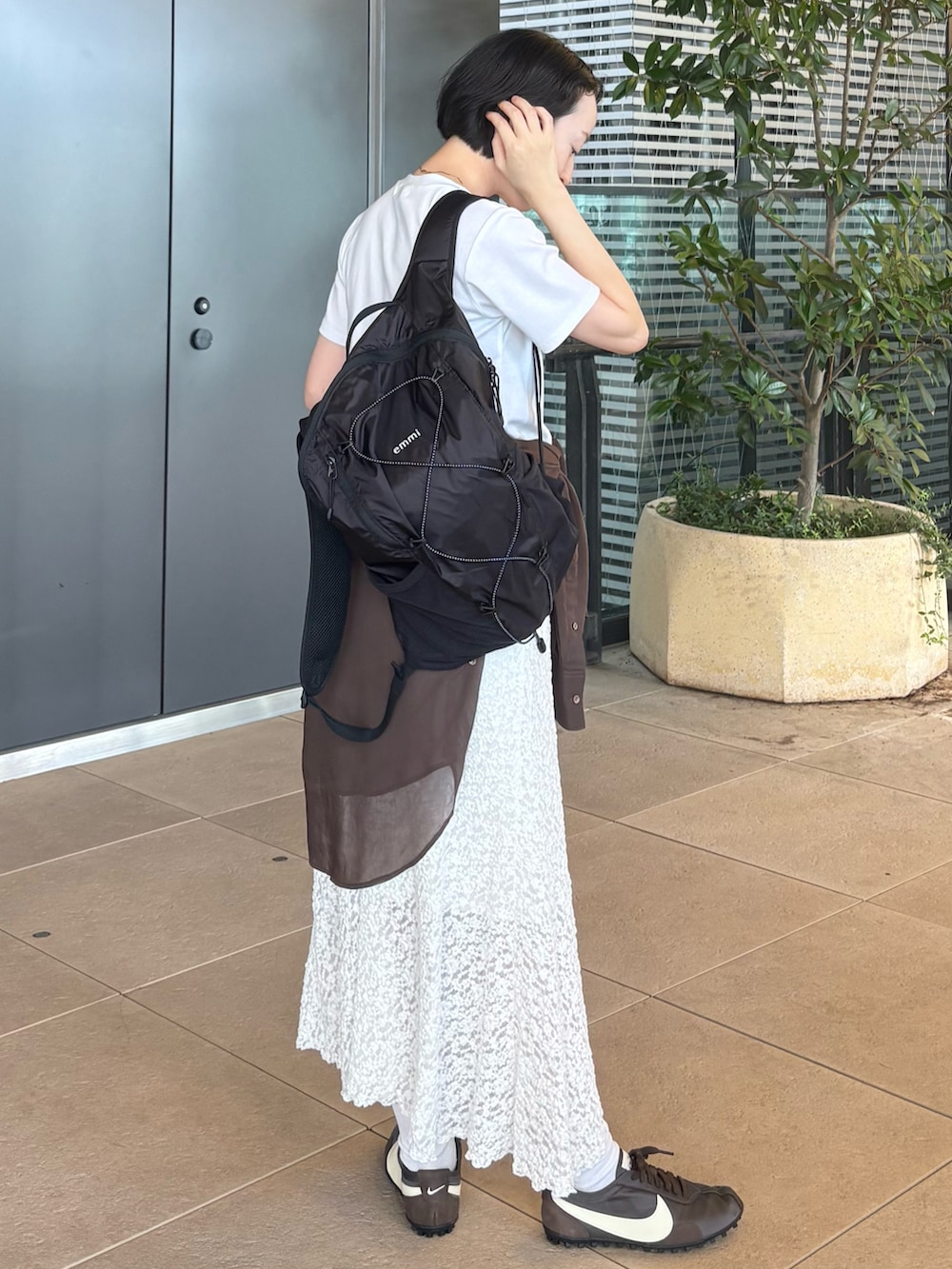 ホワイト系のTシャツ/カットソー、ホワイト系のスカート、ブラック系のバックパック/リュックを着用したレディースの夏コーディネートの2枚目の写真