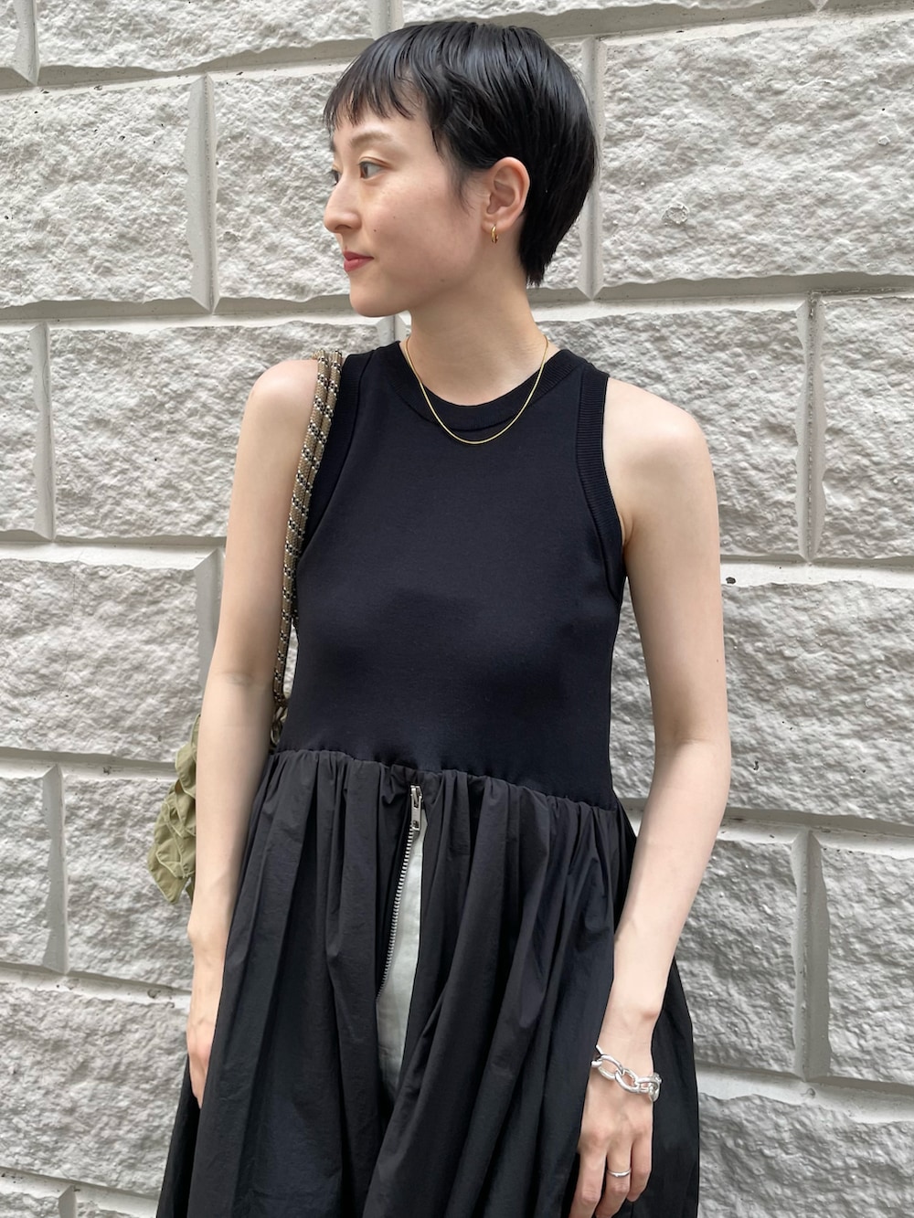 ブラック系のワンピース、グリーン系のショルダーバッグ、ホワイト系のデニムパンツを着用したレディースの夏コーディネートの3枚目の写真