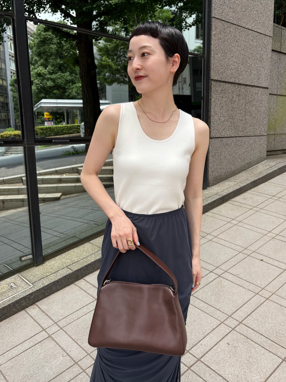 ホワイト系のタンクトップ、ブルー系のスカート、ブラウン系のショルダーバッグを着用したレディースの夏コーディネートの2枚目の写真