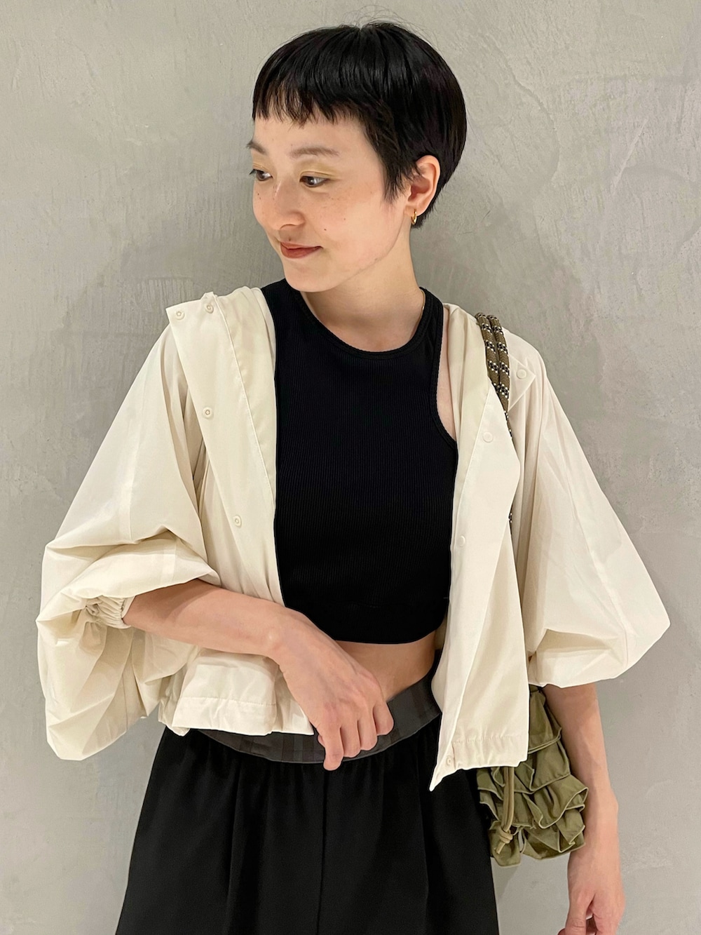 ブラック系のタンクトップ、ホワイト系のナイロンジャケット、ブラック系のスラックスを着用したレディースの夏コーディネートの4枚目の写真