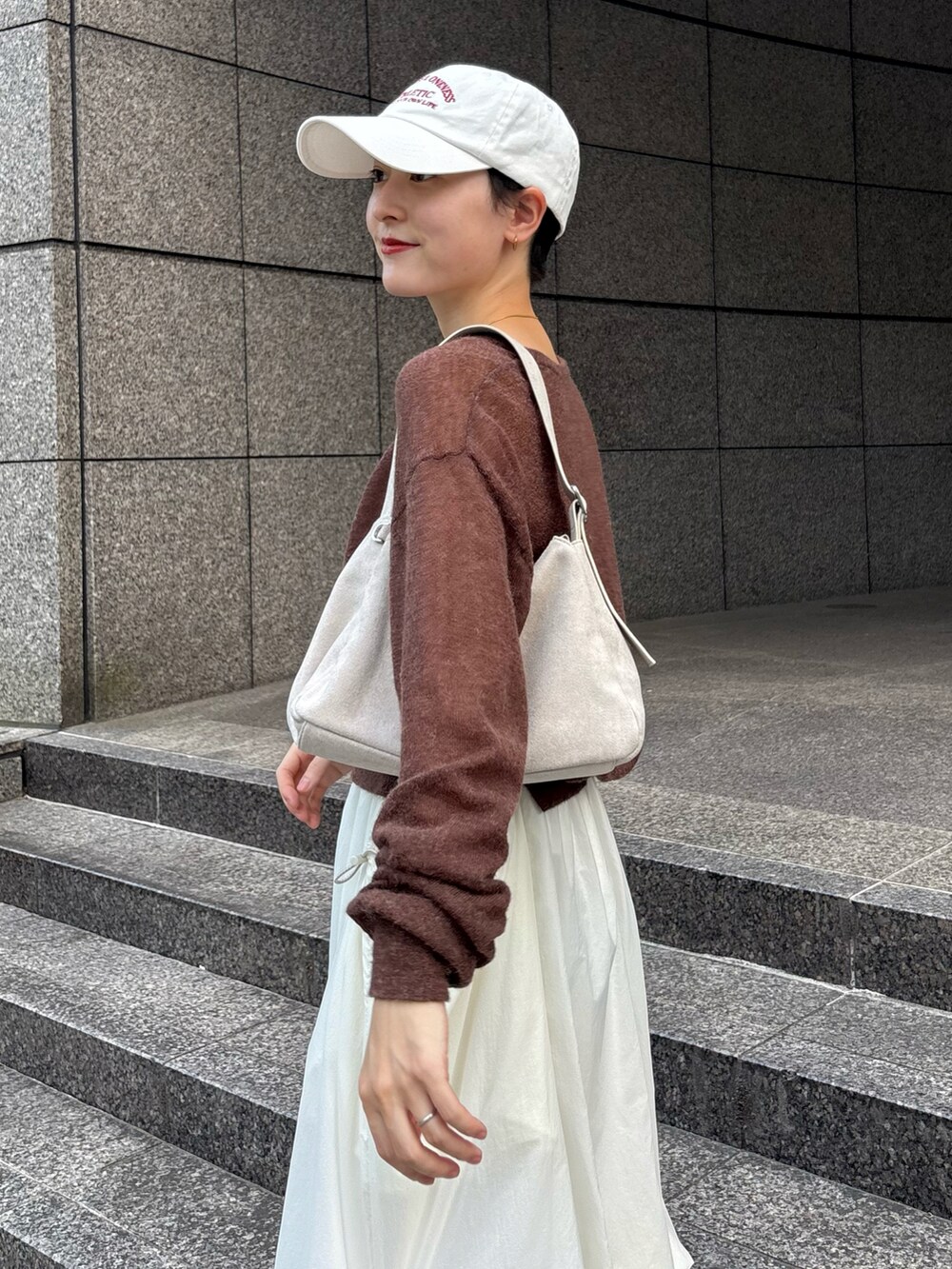 ブラウン系のニット/セーター、グレー系のショルダーバッグ、ホワイト系のスカートを着用したレディースの秋コーディネートの4枚目の写真