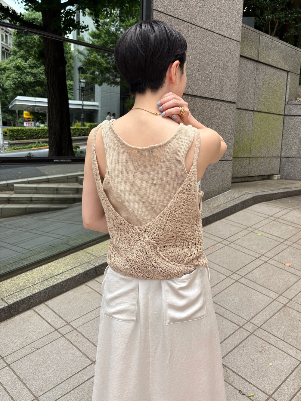 ベージュ系のニット/セーター、ベージュ系のスカート、レッド系のハンドバッグを着用したレディースの夏コーディネートの5枚目の写真