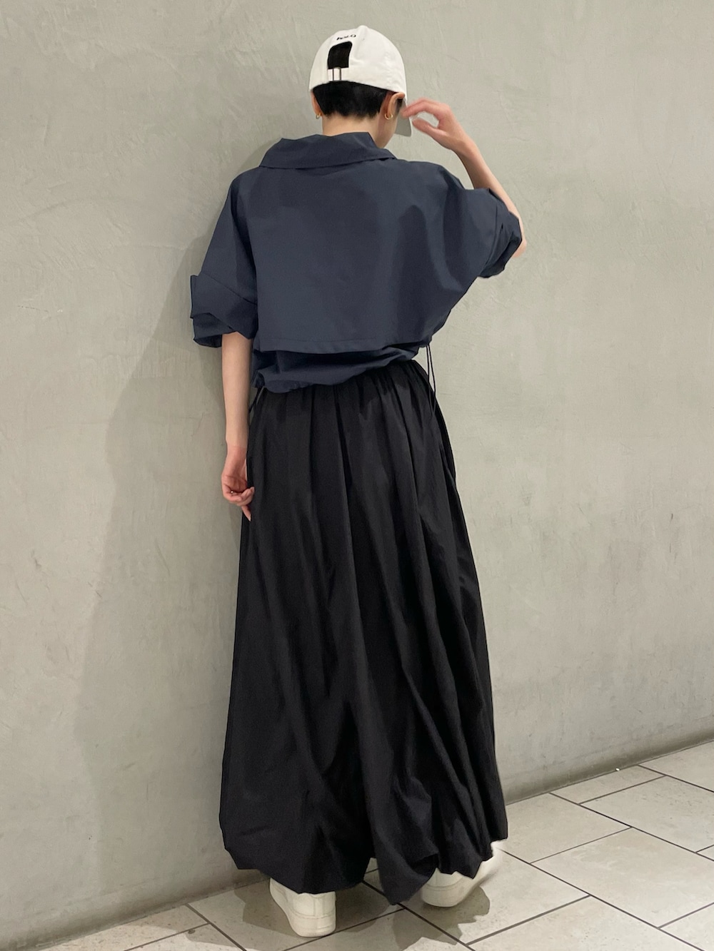 ブルー系のナイロンジャケット、ブラック系のスカート、ベージュ系のスニーカーを着用したレディースの春コーディネートの3枚目の写真