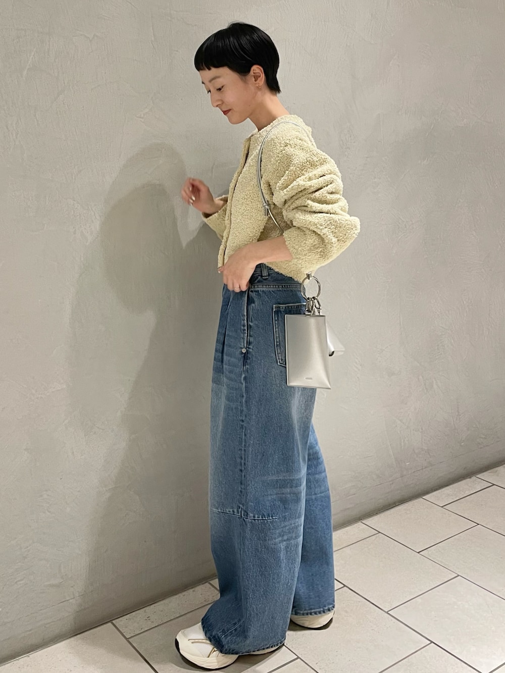 イエロー系のノーカラージャケット、シルバー系のショルダーバッグ、ブルー系のデニムパンツを着用したレディースの春コーディネートの2枚目の写真