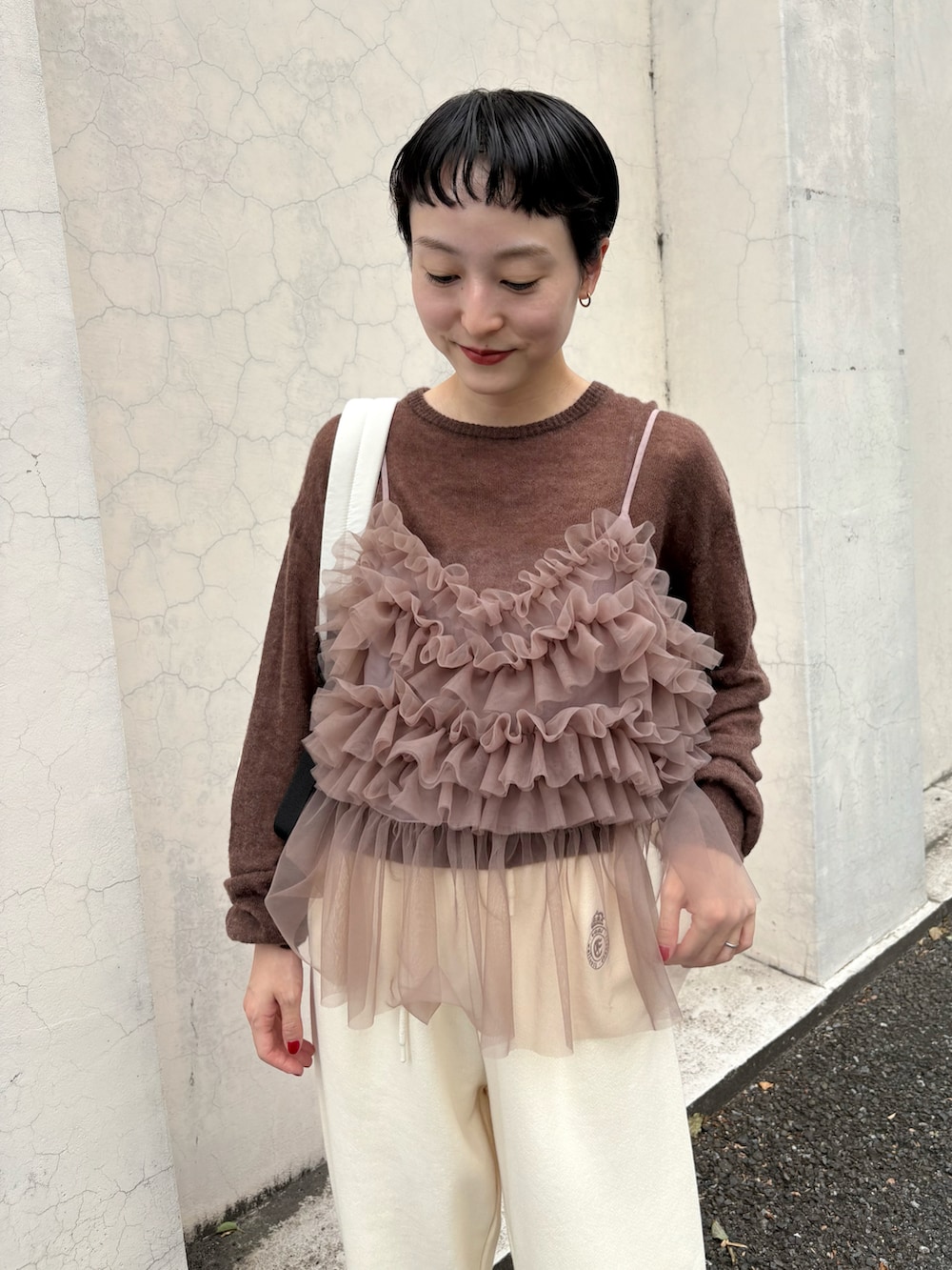 ブラウン系のニット/セーター、ブラウン系のTシャツ/カットソー、ホワイト系のスウェットパンツを着用したレディースの秋コーディネートの3枚目の写真