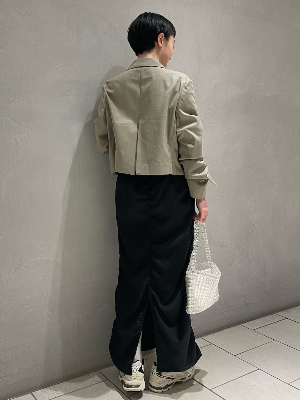 グリーン系のテーラードジャケット、ブラック系のキャミソール、ブラック系のスカートを着用したレディースの春コーディネートの3枚目の写真