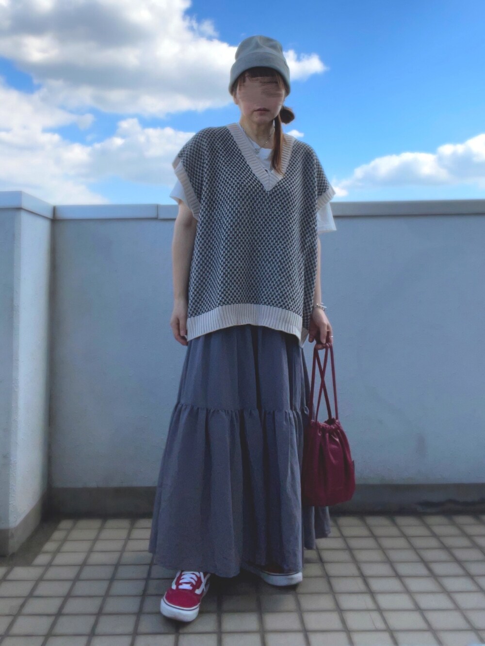 ホワイト系のベスト、グレー系のスカート、レッド系のバッグを着用したレディースの秋コーディネートの3枚目の写真