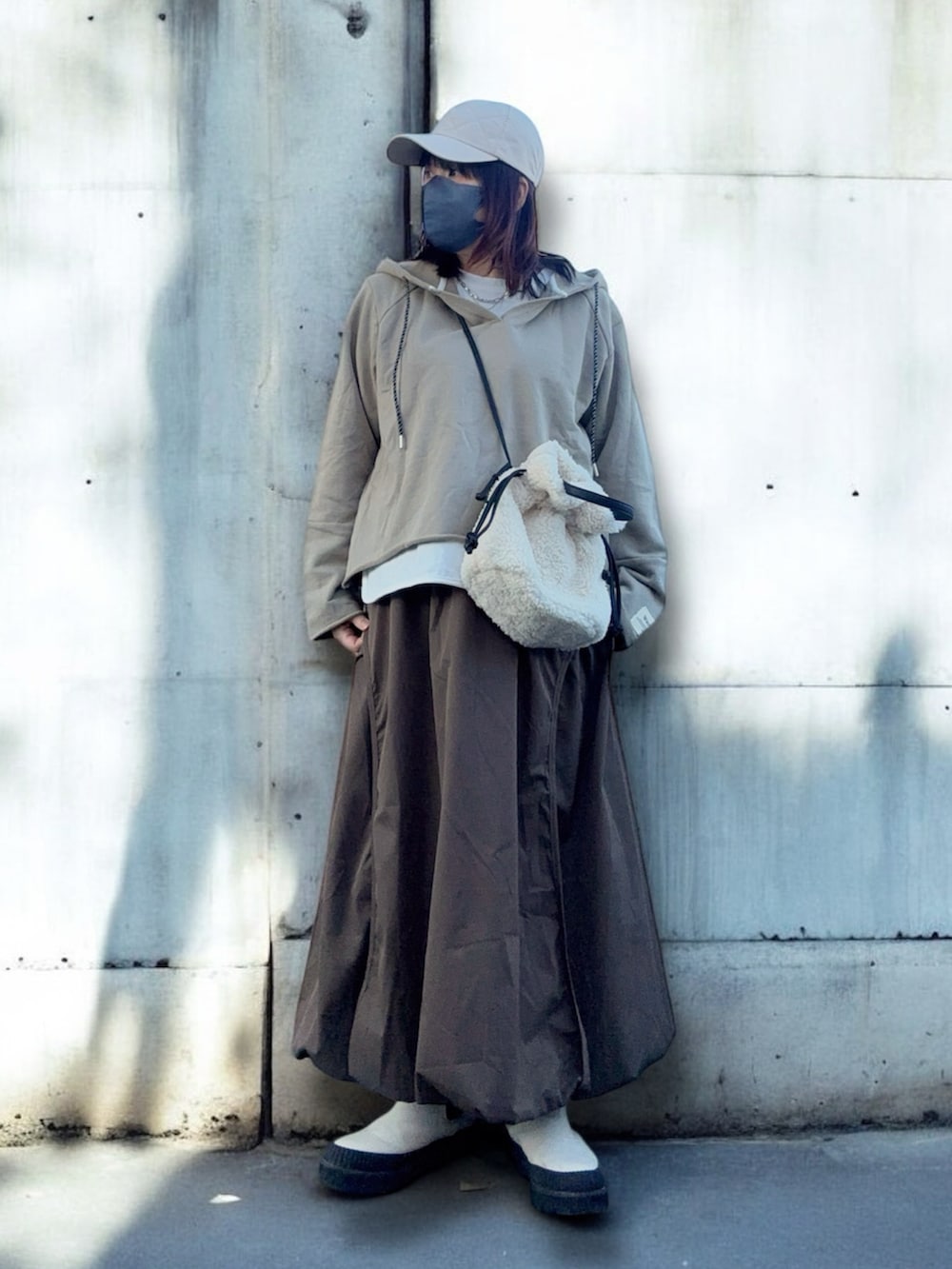 ホワイト系のブーツ、ベージュ系のトップス、ブラウン系のスカートを着用したレディースの冬コーディネートの2枚目の写真