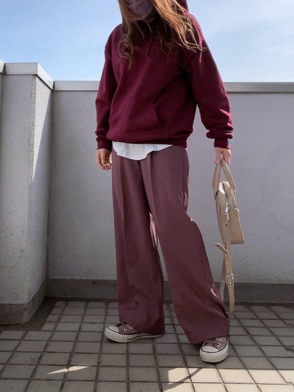 レッド系のパーカー、パープル系のその他パンツ、ベージュ系のハンドバッグを着用したレディースの冬コーディネートの2枚目の写真