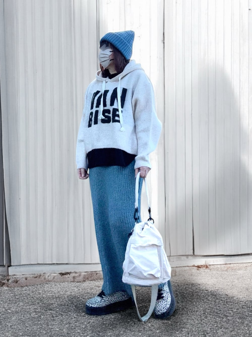 ブルー系のスカート、ブラウン系のスニーカー、ホワイト系のメッセンジャーバッグを着用したレディースの冬コーディネートの2枚目の写真