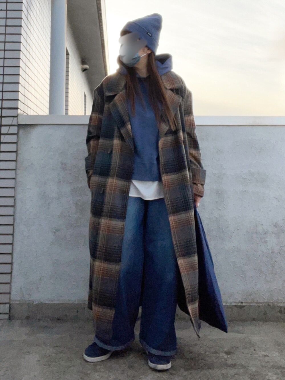 ブラウン系のチェスターコート、ブルー系のパーカー、ブルー系のスニーカーを着用したレディースの冬コーディネートの3枚目の写真
