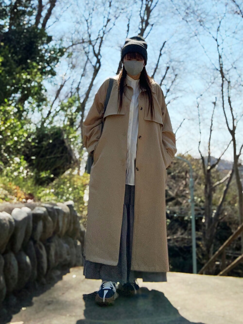 ベージュ系のトレンチコート、ホワイト系のシャツ/ブラウス、グレー系のスカートを着用したレディースの春コーディネートの5枚目の写真