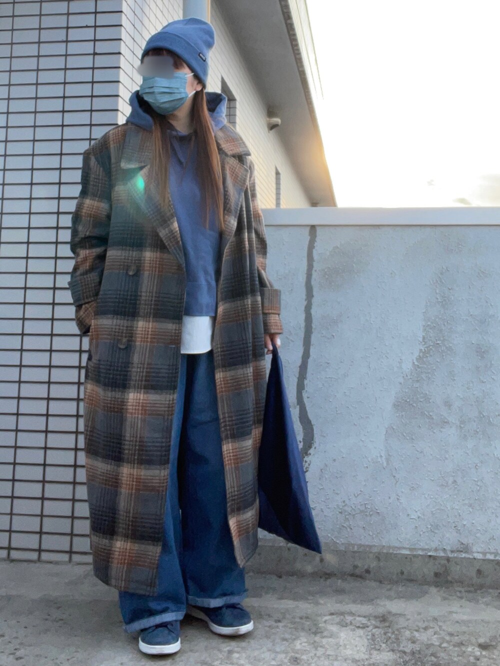 ブラウン系のチェスターコート、ブルー系のパーカー、ブルー系のスニーカーを着用したレディースの冬コーディネートの2枚目の写真