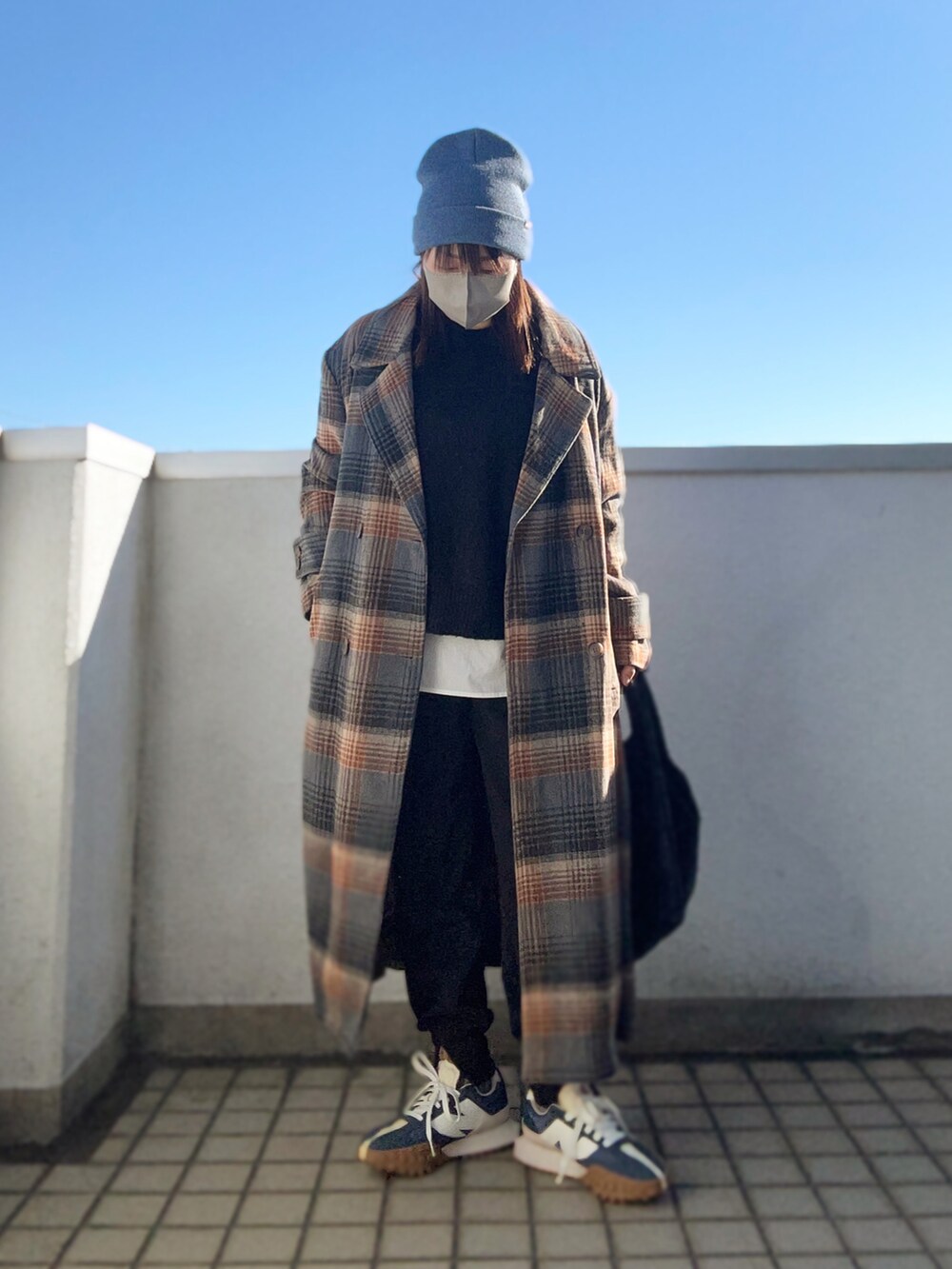 ブラウン系のチェスターコート、ブラック系のニット/セーター、ブラック系のその他パンツを着用したレディースの冬コーディネートの2枚目の写真