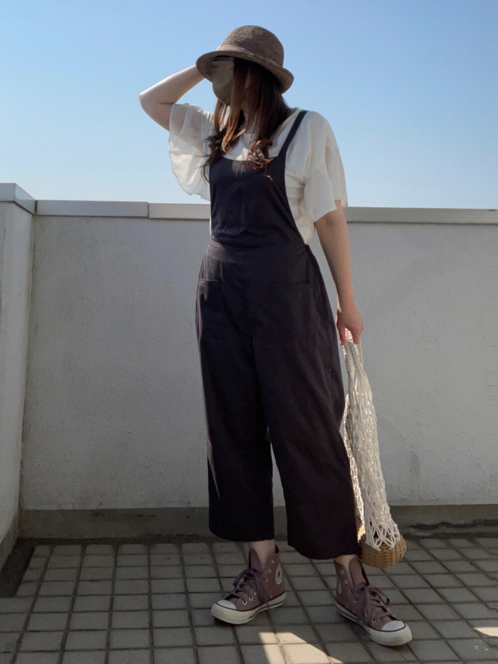 ブラウン系のスニーカー、ホワイト系のかごバッグ、ブラウン系のハットを着用したレディースの夏コーディネートの2枚目の写真