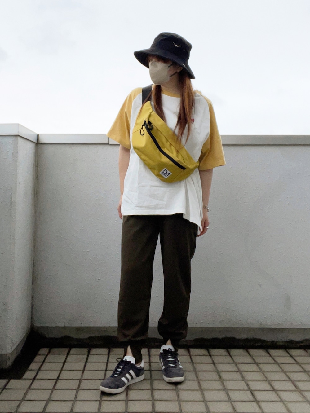 イエロー系のTシャツ/カットソー、グレー系のスニーカー、ブラック系の帽子を着用したレディースの夏コーディネートの2枚目の写真