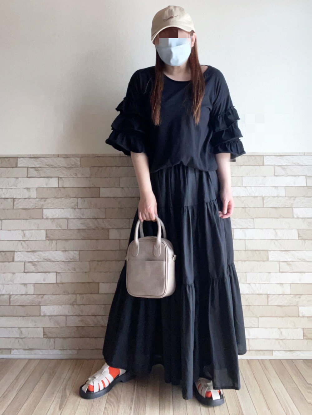 ブラック系のTシャツ/カットソー、ブラック系のスカート、ベージュ系のハンドバッグを着用したレディースの春コーディネートの2枚目の写真