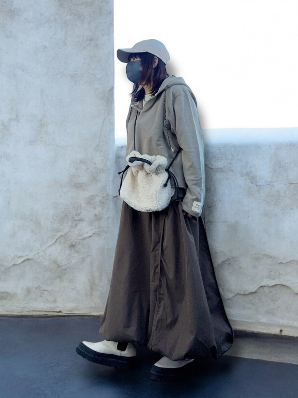 ホワイト系のブーツ、ベージュ系のトップス、ブラウン系のスカートを着用したレディースの冬コーディネートの3枚目の写真