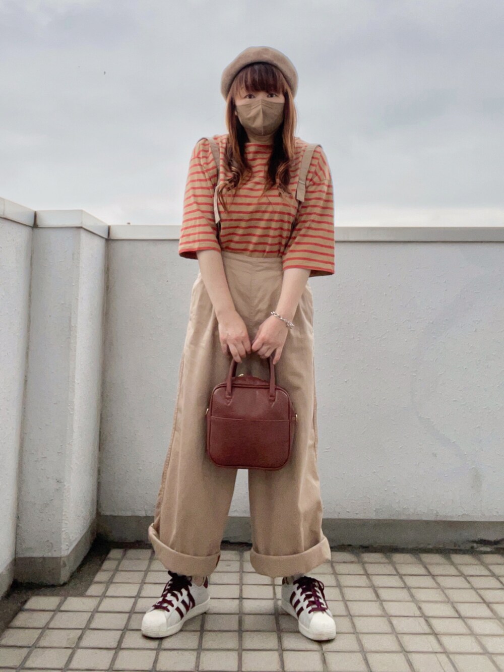 イエロー系のTシャツ/カットソー、ブラウン系のボストンバッグ、ホワイト系のスニーカーを着用したレディースの夏コーディネートの2枚目の写真