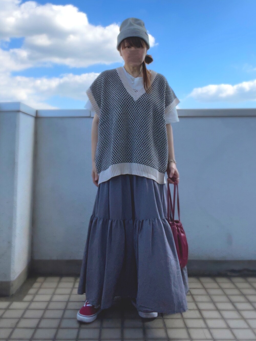 ホワイト系のベスト、グレー系のスカート、レッド系のバッグを着用したレディースの秋コーディネートの2枚目の写真