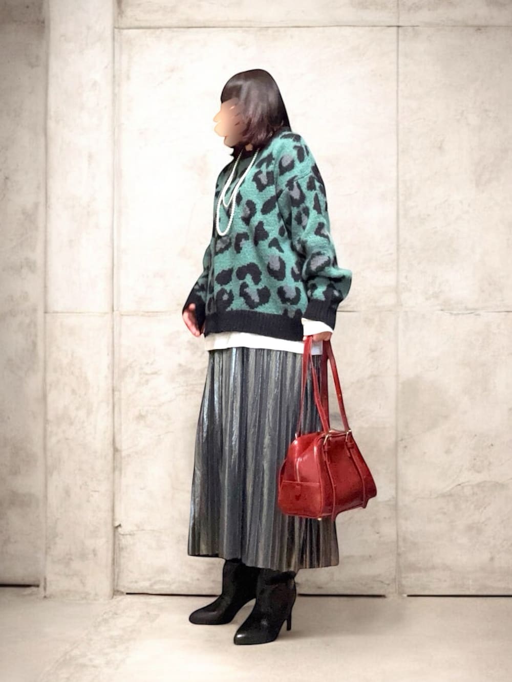 レッド系のボストンバッグ、グリーン系のニット/セーター、ホワイト系のカバーオールを着用したレディースの冬コーディネートの2枚目の写真