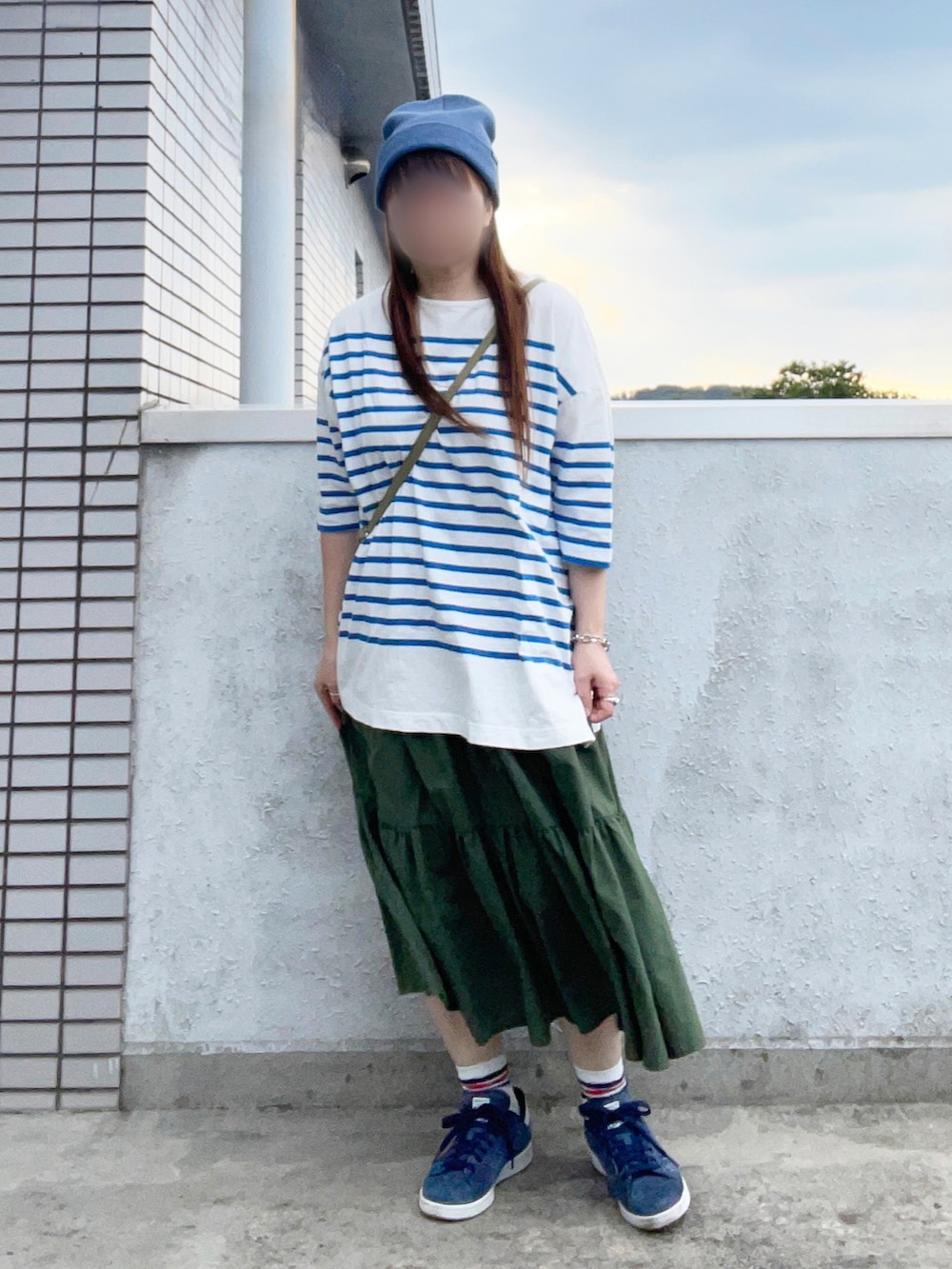 グリーン系のショルダーバッグ、グリーン系のスカート、ブルー系のTシャツ/カットソーを着用したレディースの秋コーディネートの2枚目の写真