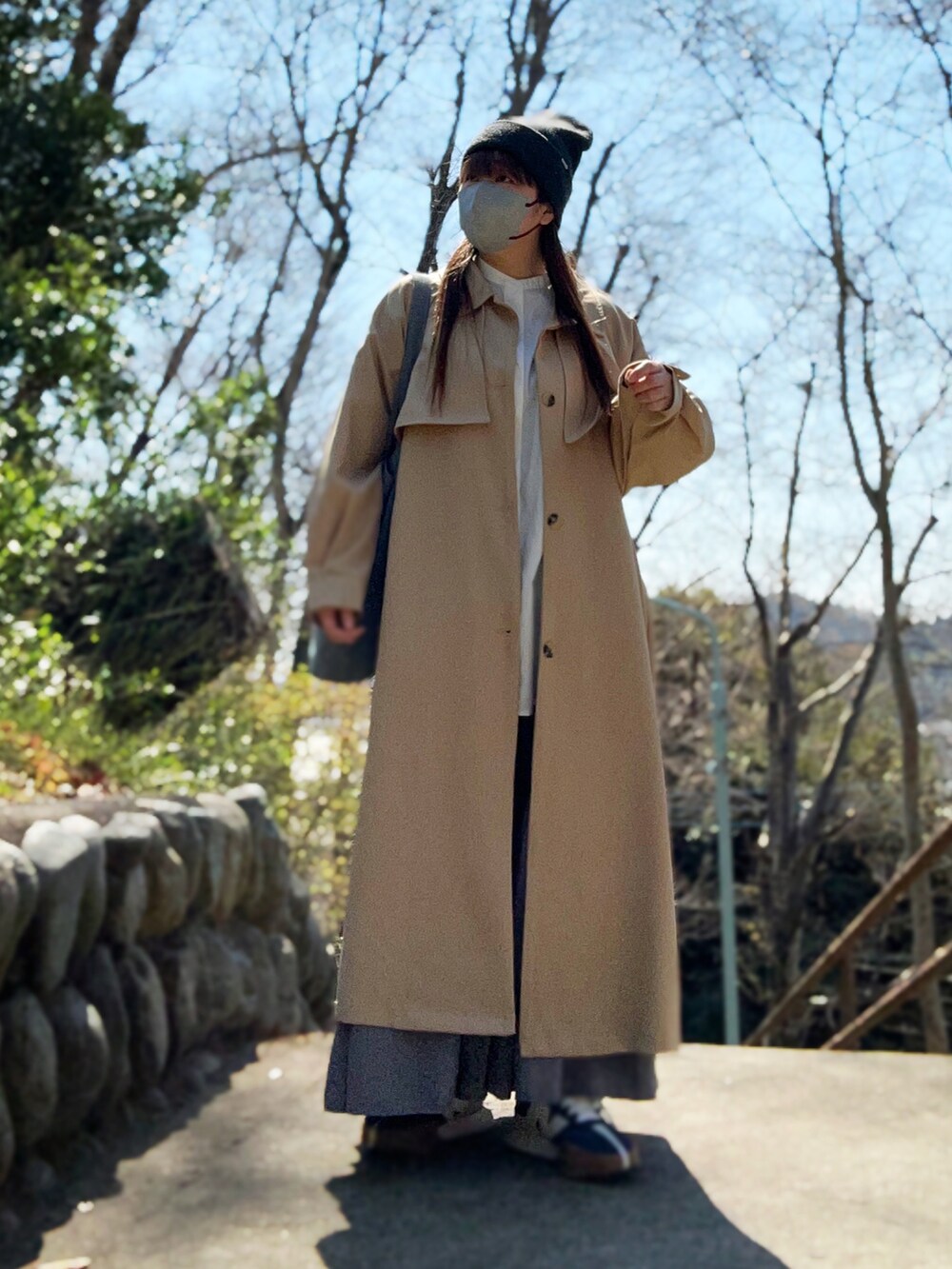 ベージュ系のトレンチコート、ホワイト系のシャツ/ブラウス、グレー系のスカートを着用したレディースの春コーディネートの4枚目の写真
