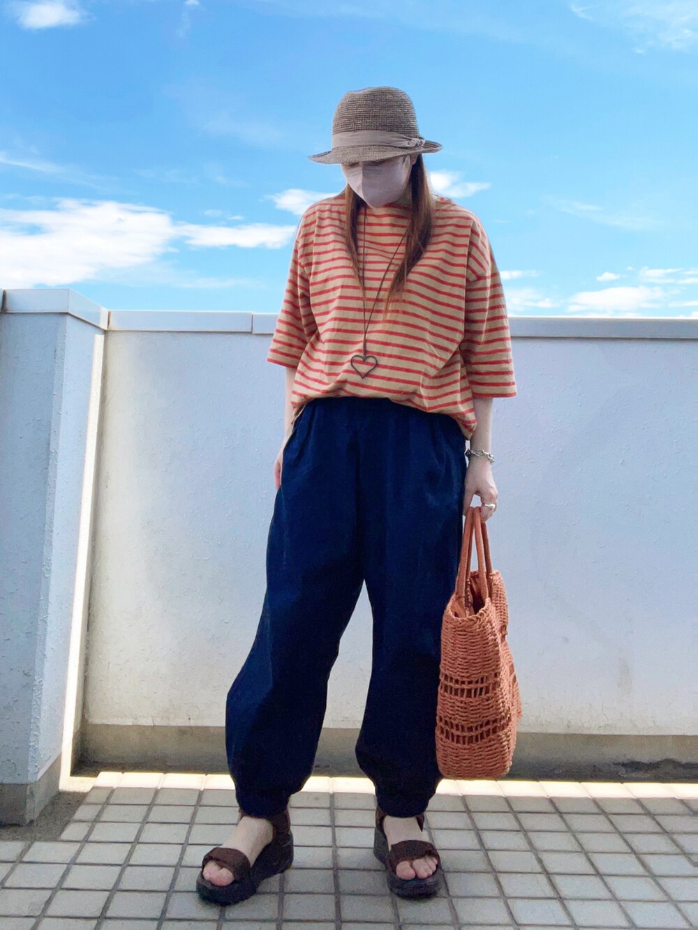 イエロー系のTシャツ/カットソー、ブルー系のデニムパンツ、ブラウン系のトートバッグを着用したレディースの夏コーディネートの2枚目の写真