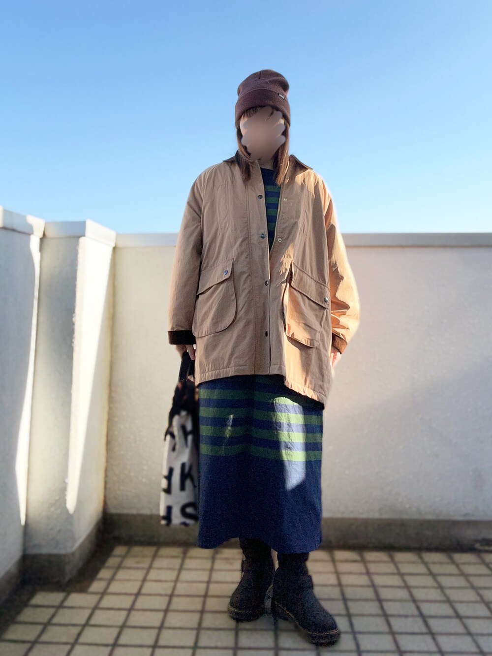 ベージュ系のブルゾン、ブルー系のワンピース、ブラック系のブーツを着用したレディースの秋コーディネートの2枚目の写真