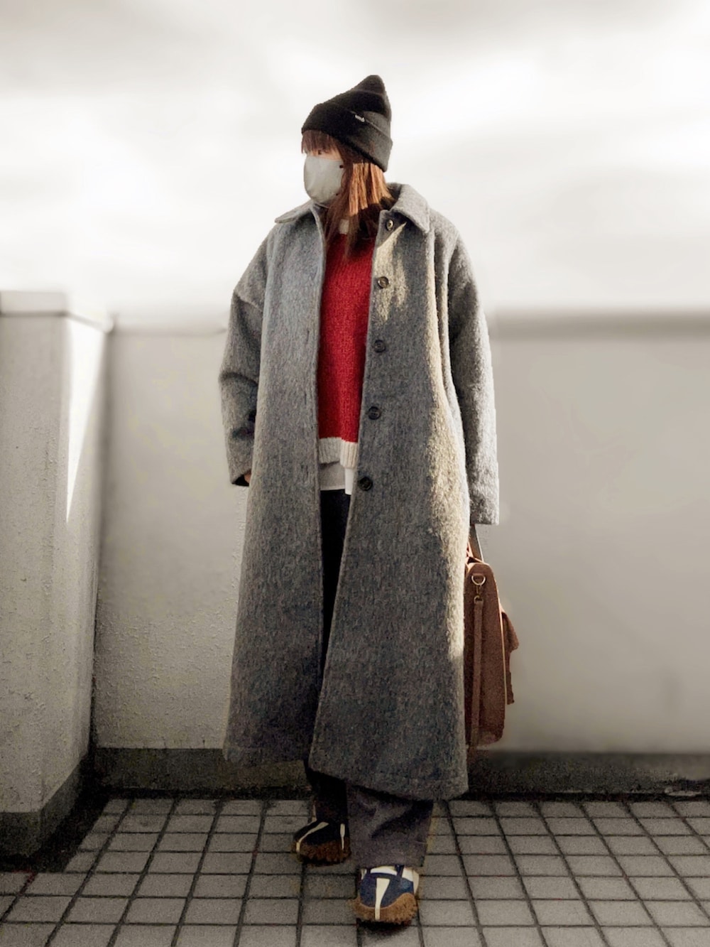 レッド系のニット/セーター、グレー系のパンツ、ブルー系のスニーカーを着用したレディースの冬コーディネートの2枚目の写真