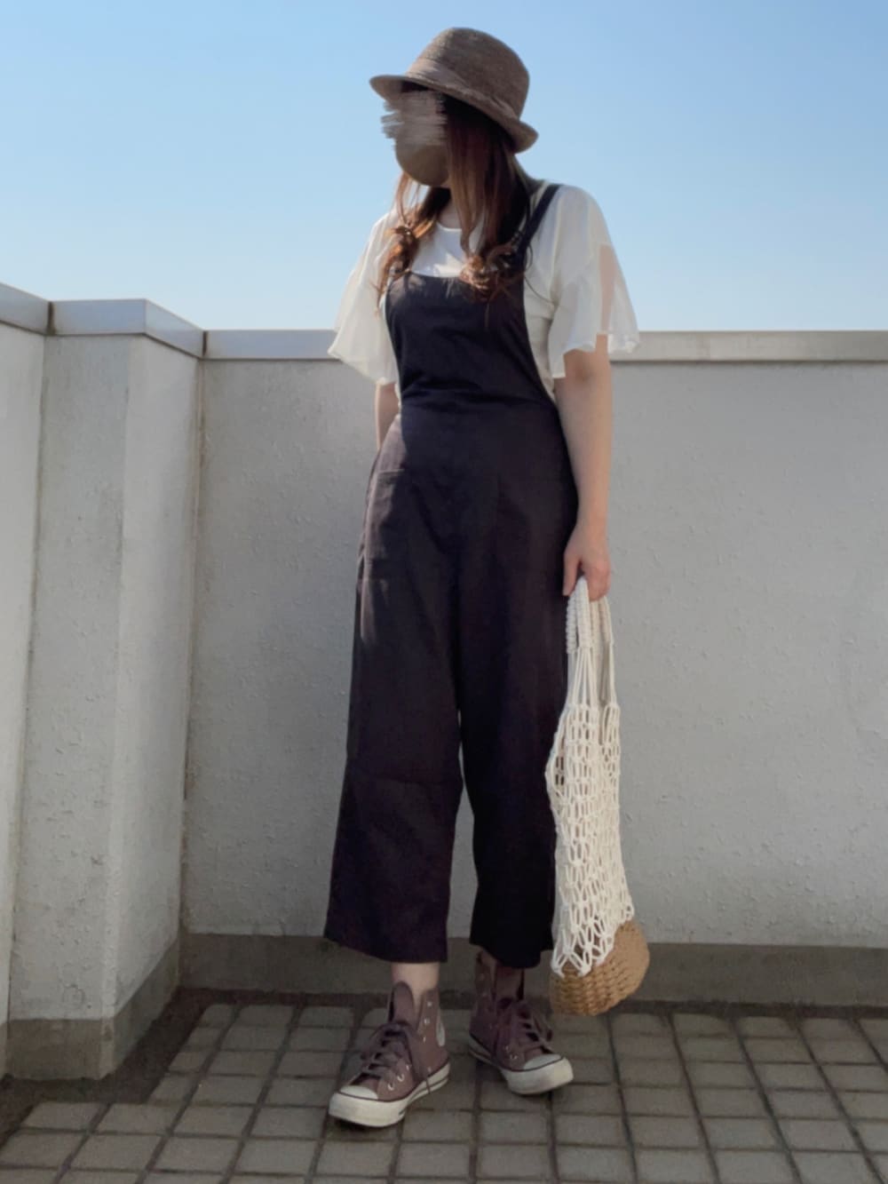 ブラウン系のスニーカー、ホワイト系のかごバッグ、ブラウン系のハットを着用したレディースの夏コーディネートの4枚目の写真