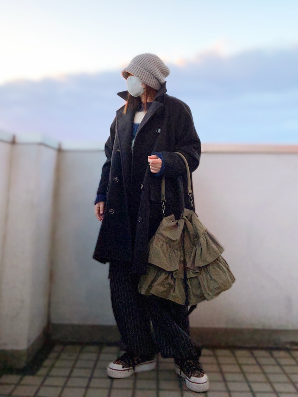 ブラック系のピーコート、ブルー系のニット/セーター、グレー系のカーゴパンツを着用したレディースの冬コーディネートの2枚目の写真