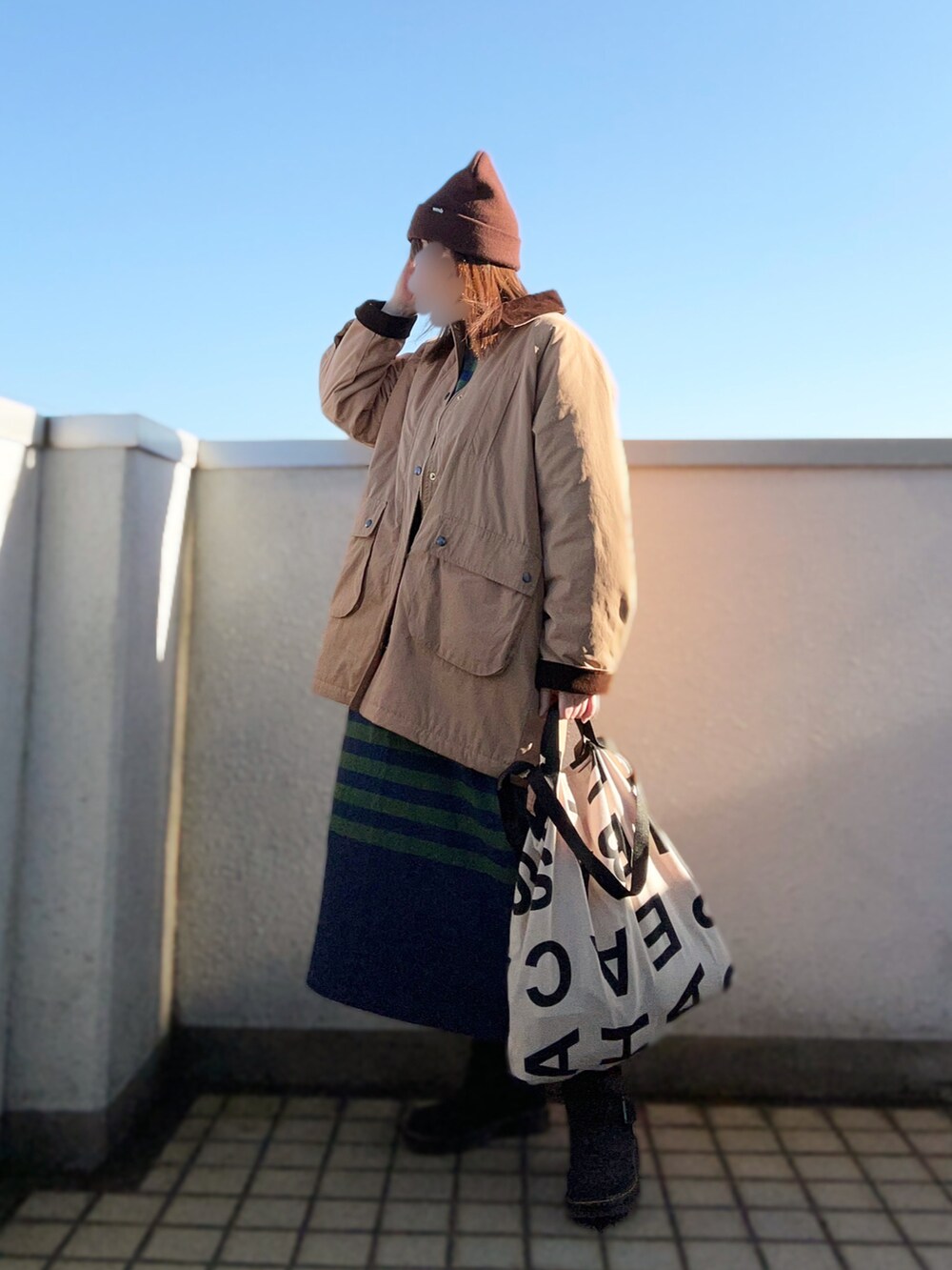 ベージュ系のブルゾン、ブルー系のワンピース、ブラック系のブーツを着用したレディースの秋コーディネートの3枚目の写真