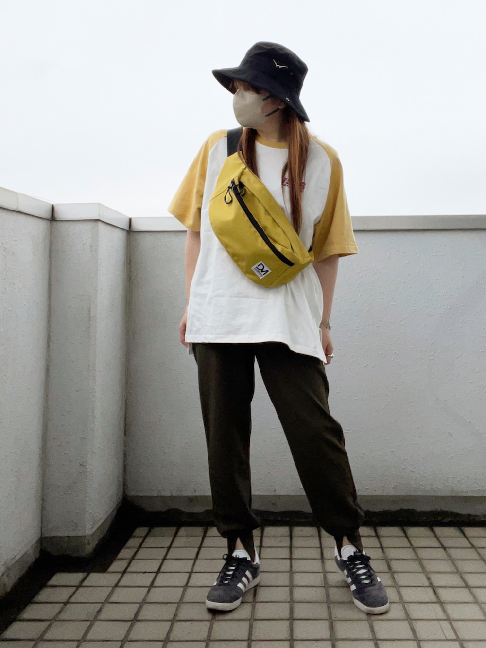 イエロー系のTシャツ/カットソー、グレー系のスニーカー、ブラック系の帽子を着用したレディースの夏コーディネートの3枚目の写真