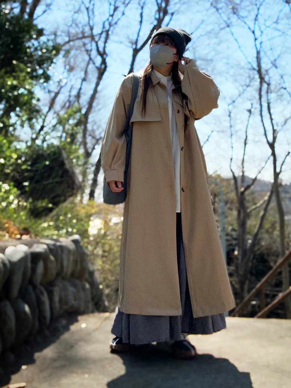 ベージュ系のトレンチコート、ホワイト系のシャツ/ブラウス、グレー系のスカートを着用したレディースの春コーディネートの3枚目の写真